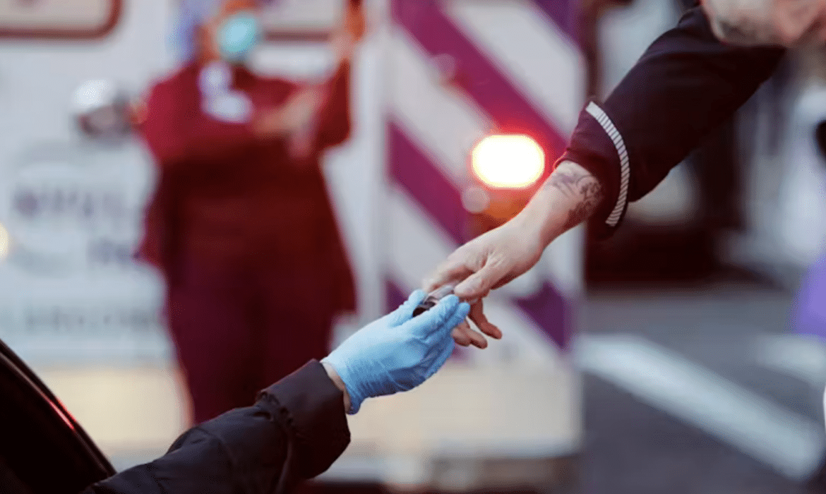 A hand with a blue surgical glove on it reaches up to a woman's bare hand.